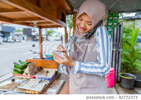 muslim seller taking order from customer through phone muslim seller taking order from customer through phone 92772373
