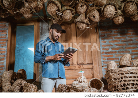 male entrepreneur in hat using tablet standing close to craft male entrepreneur in hat using tablet standing close to craft 92772374