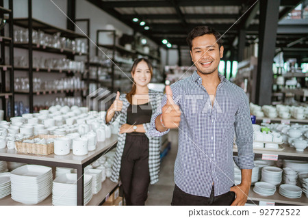 Young asian man smiling while standing with thumbs up 92772522