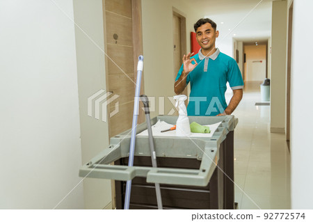 housekeepers with okay hand gestures push carts filled with tools 92772574