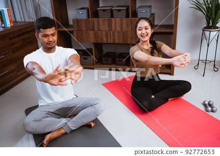 Asian fitness couple stretching at home. exercising together in livingroom Asian fitness couple stretching at home. exercising together in livingroom 92772653