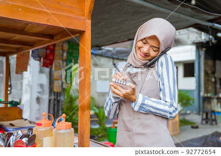 muslim seller taking order from customer through phone muslim seller taking order from customer through phone 92772654
