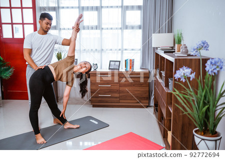 Asian fitness couple stretching at home. exercising together in livingroom Asian fitness couple stretching at home. exercising together in livingroom 92772694