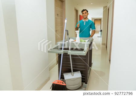 housekeepers with thumbs up pushing carts filled with cleaning supplies 92772796