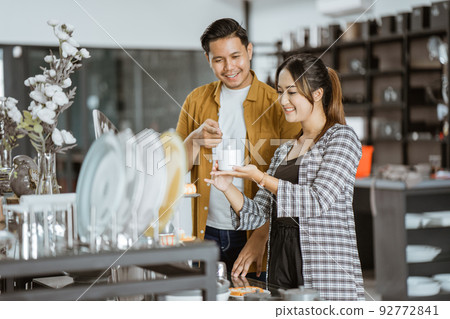 Young asian couple looking at choosing ceramic cups Young asian couple looking at choosing ceramic cups 92772841