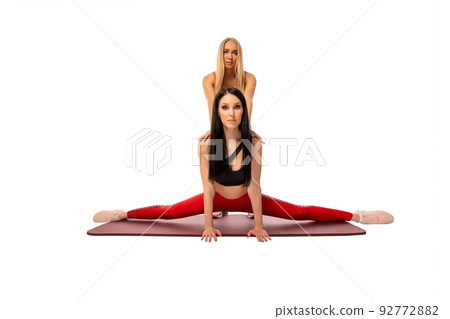 Young woman practicing split exercise with female coach Young woman practicing split exercise with female coach 92772882