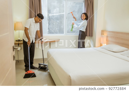 two cleaning staff working cleaning the room with cleaning equipment two cleaning staff working cleaning the room with cleaning equipment 92772884