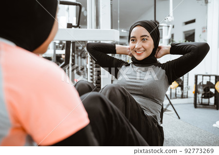 muslim woman sitting up exercise with partner at the gym muslim woman sitting up exercise with partner at the gym 92773269