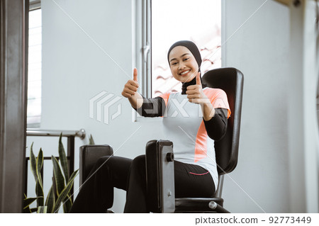 asian woman working on her lower body using leg machine asian woman working on her lower body using leg machine 92773449