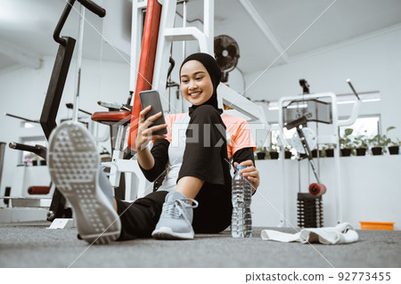 beautiful muslim sporty woman taking a break after exercising using phone beautiful muslim sporty woman taking a break after exercising using phone 92773455