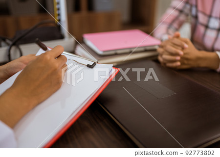 close up of doctor's hand writing on paper for patient 92773802