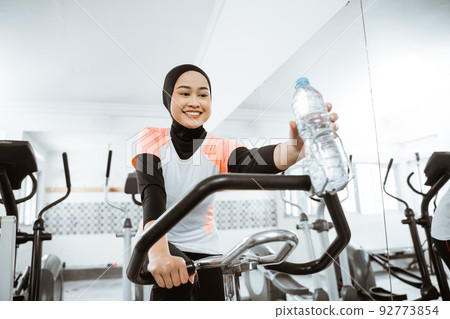 women muslim using static elliptical cycle machine at the gym 92773854