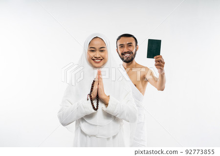 husband and wife wearing ihram clothes holding a passport husband and wife wearing ihram clothes holding a passport 92773855
