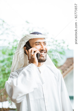 man in a turban is calling using a mobile phone while smiling man in a turban is calling using a mobile phone while smiling 92773857
