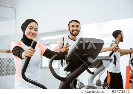 women muslim using static elliptical cycle machine at the gym 92773862