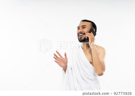 Man wearing ihram clothes using cellphone to make calls Man wearing ihram clothes using cellphone to make calls 92773926