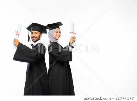 Happy graduate couple in black toga holding rolls of certificate Happy graduate couple in black toga holding rolls of certificate 92774177