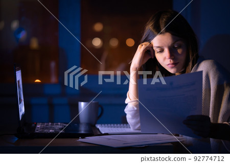 Girl is working on a laptop at night at home. Girl is working on a laptop at night at home. 92774712