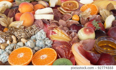 assorted fruits, berries, cheese, sausage, snacks and honey on a tray. assorted fruits, berries, cheese, sausage, snacks and honey on a tray. 92774888