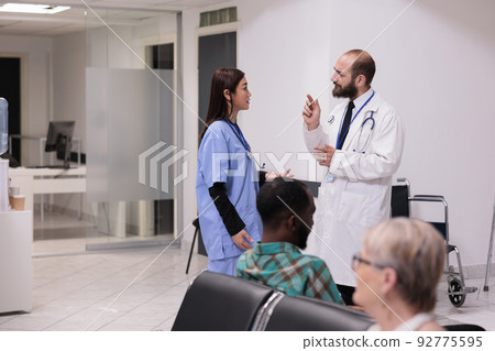 Diverse medical team talking about healthcare support in hospital reception, discussing about patients and appointments at medical facility lobby. Doctor and nurse in waiting room area. Diverse medical team talking about healthcare support in hospital reception, discussing about patients and appointments at medical facility lobby. Doctor and nurse in waiting room area. 92775595