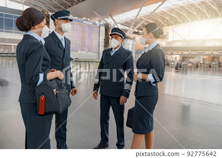 Plane team in masks talking in airport terminal Plane team in masks talking in airport terminal 92775642