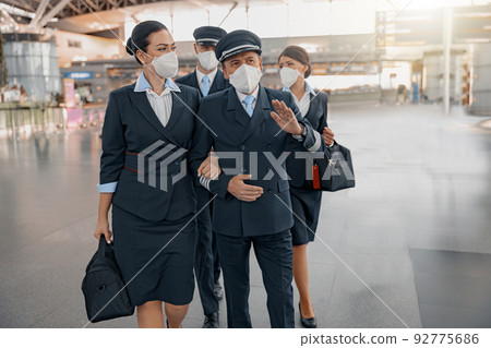 Male pilots and female flight attendants walking in airport terminal together 92775686