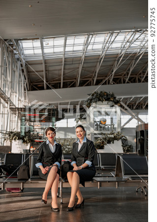 Two flight attendants sitting on the seats in the airport terminal 92775745