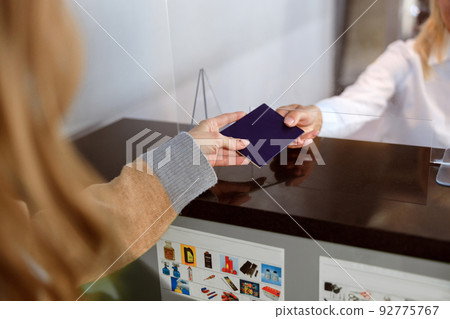 Woman handing over her passport at passport control at the airport 92775767