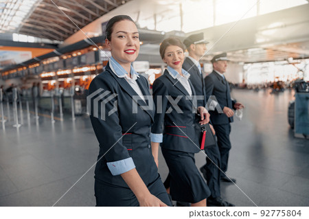 Two flight attendants and pilots walking through the terminal to the plane 92775804
