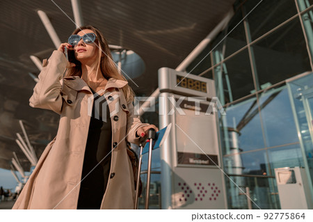 Young woman using smartphone near the entrance to the airport 92775864