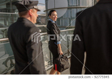 Flight attendant holding a bag and looking back at the pilots 92775945