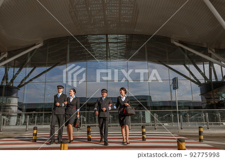 Flight team crossing the road outdoor with terminal on the background Flight team crossing the road outdoor with terminal on the background 92775998