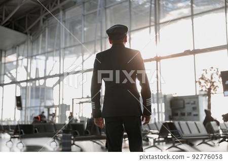 Male pilot in uniform standing in airport terminal 92776058