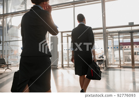 Two stewardesses walking to the airport terminal exit 92776093