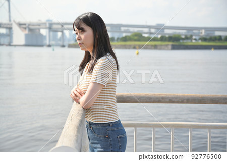 A woman looking at the sea from a pier in Odaiba 92776500