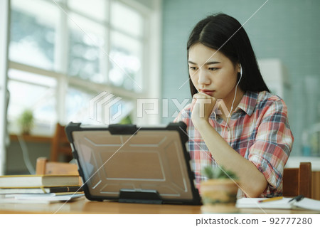 Young asian woman study in front of the laptop computer and and using headphones at offsite.. 92777280