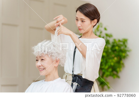 Hairdresser cutting hair of gray-haired woman 92778060