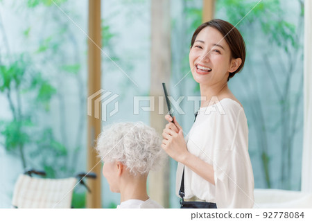 Portrait of a hairdresser cutting hair of a gray-haired woman 92778084