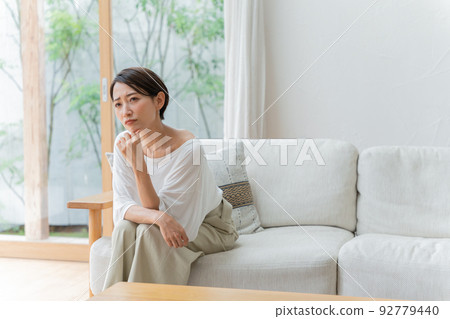 Middle woman thinking in the living room Middle woman thinking in the living room 92779440