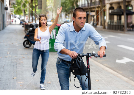 Man riding kick scooter with handbag after stole this from emotional female 92782293