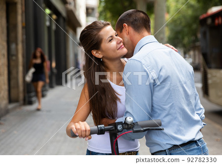 Hugging couple riding electro scooter Hugging couple riding electro scooter 92782330