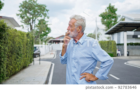 An old senior man smoking cigarette outside, smoke addiction, bad habbit. 92783646