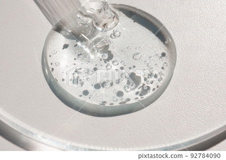 Pipette with sample of gels cosmetic product in petri dish on white background, hard shadows 92784090