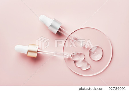 Two pipettes with different samples of gels cosmetic products in petri dish on pink background 92784091