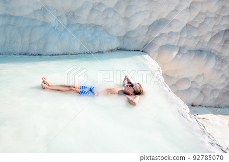 Little kid enjoy hot spring spa at Pamukkale while lying in hot spring water in Turkey. Pamukkale means cotton castle in Turkish. People have bathed in outdoor swiming pools. Child boy in sunglasses. Little kid enjoy hot spring spa at Pamukkale while lying in hot spring water in Turkey. Pamukkale means cotton castle in Turkish. People have bathed in outdoor swiming pools. Child boy in sunglasses. 92785070