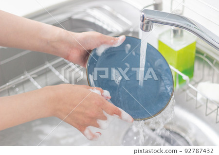 A woman washing dishes 92787432