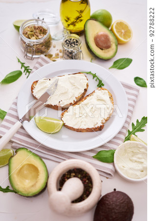Avocado and cream cheese toasts preparation - grilled or toasted bread with cheese smeared  92788222