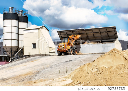 A large front loader transports materials in a concrete production plant. Production of concrete. Transportation of bulk materials. Construction equipment. Bulk cargo transportation. A large front loader transports materials in a concrete production plant. Production of concrete. Transportation of bulk materials. Construction equipment. Bulk cargo transportation. 92788785