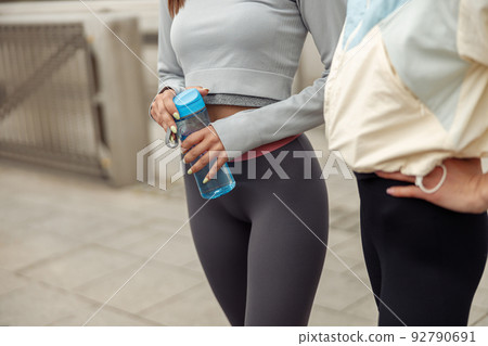 Close up of two young sporty woman have a rest after morning running in city Close up of two young sporty woman have a rest after morning running in city 92790691