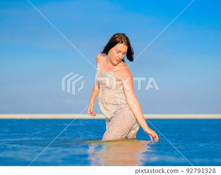 A young girl in a wet sundress bathes in the sea 92791328